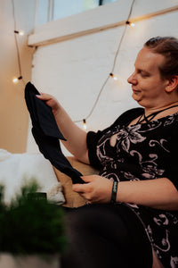 Frau mit Plus Size Overknee-Strümpfen hält eine Strumpfhose in der Hand.