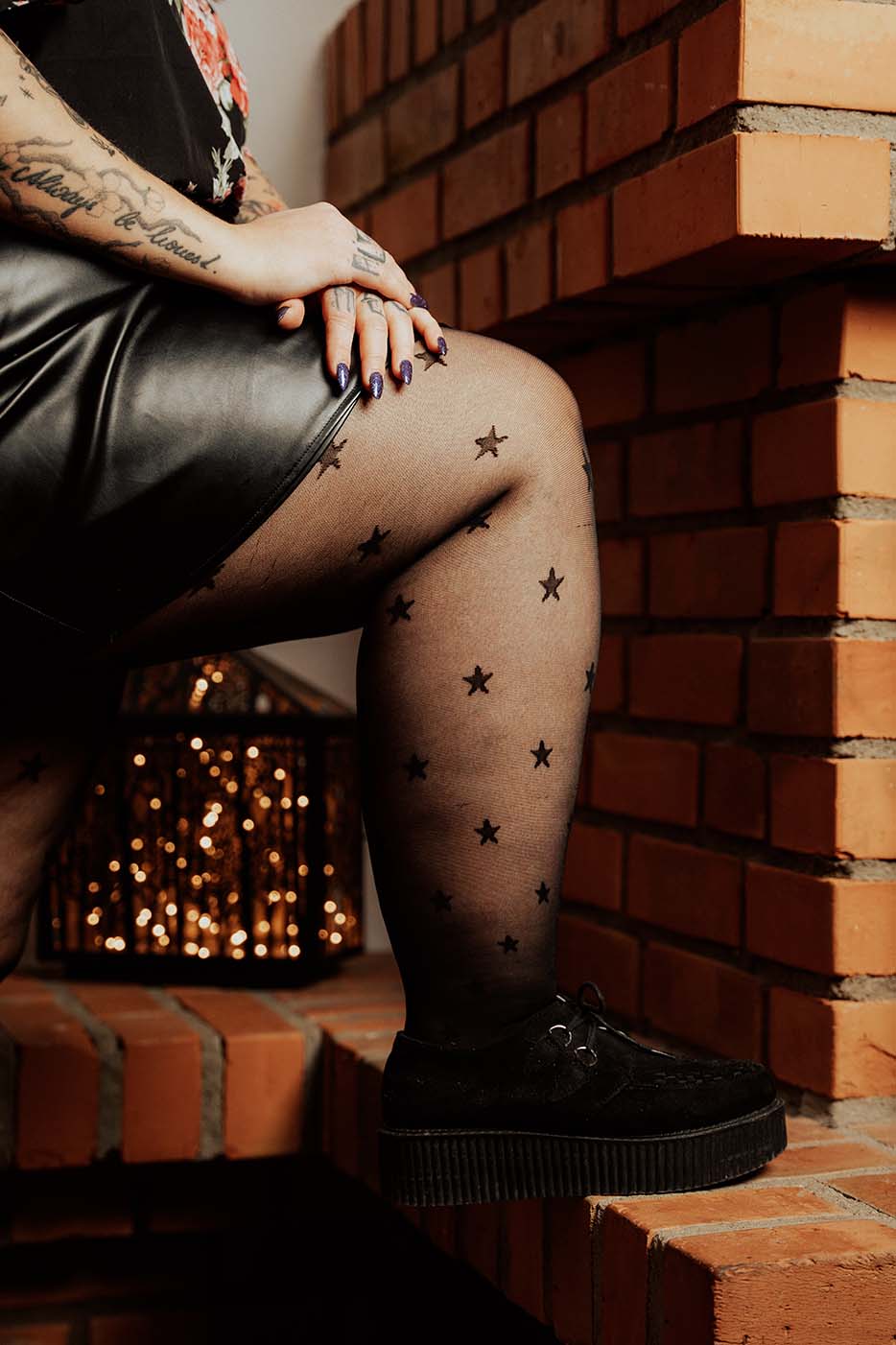 Plus Size Strumpfhose mit Sternen an Bein mit Lipödem, das aufgestützt auf einem Kaminsims steht.